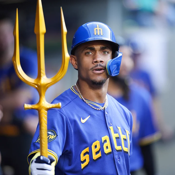 Julio Rodriguez holds the home run trident as he wears a Mariners City Connect uniform with yellow lettering.