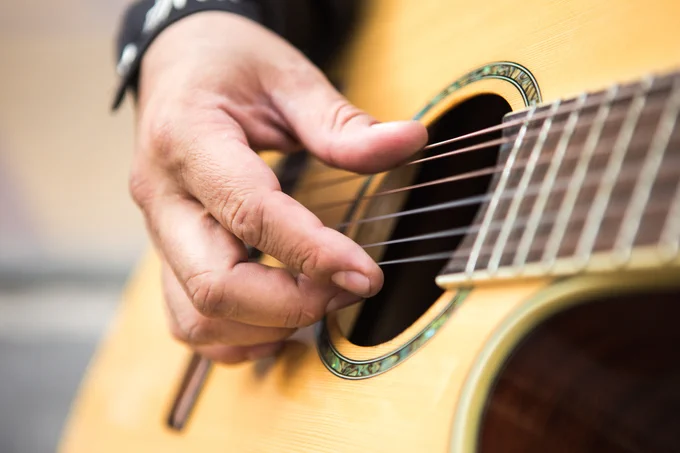 A close-up shot of a person playing the guitar.
