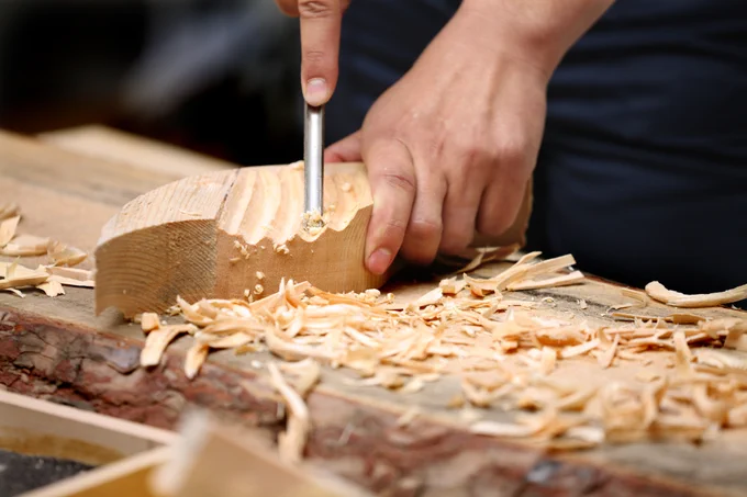 A close-up shot of a person carving into the wood.
