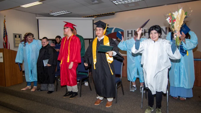 Students stand to celebrate their graduation