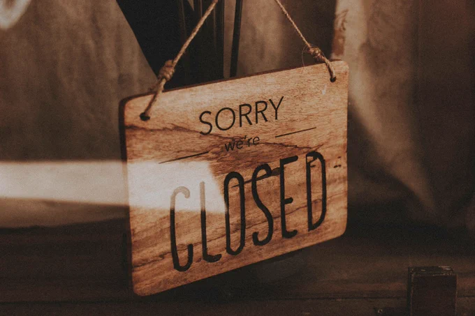 wooden sign hung up with string saying sorry we're closed