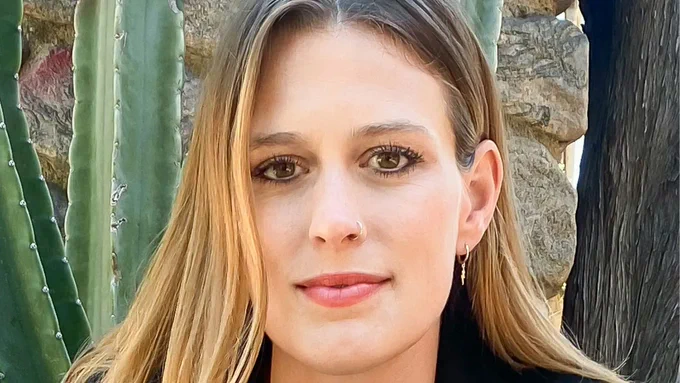 Close-up of Elizabeth Flock smiling. A cactus is in the background. Photo credit: Beowulf Sheehan