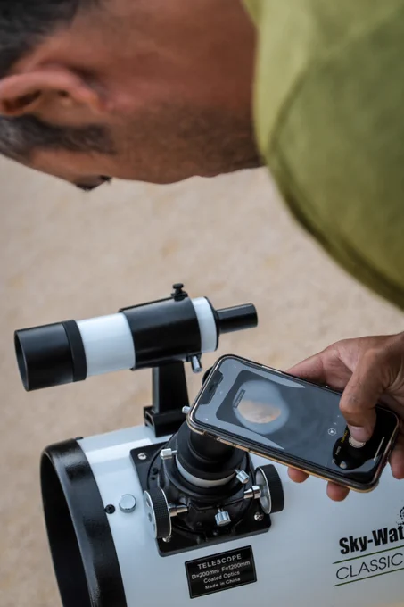 Photos de personnes observant le ciel à travers des télescopes, depuis la place Victor Hugo à Grenoble. L'un d'entre eux prend une photo avec son smartphone, d'autres posent des questions aux animateurs et animatrices présents sur place.