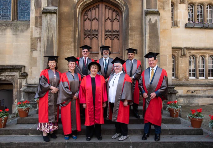 The eight honorands all smiles in their formal Oxford robes.