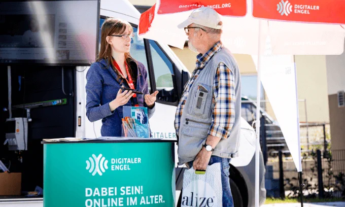 Ein älterer Herr mit Mütze lässt sich beraten. 