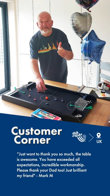 Picture of a customer with his 60th birthday gift from his family. A FlickForKicks black monochrome 5-a-side arena sits on a kitchen table with Subbuteo teams set up ready to play a game. There are balloons in the background. The testimonial caption reads: CUSTOMER CORNER. "Just want to thank you so much. The table is awesome. You have exceeded all expectations. Incredible workmanship. Please thank your Dad too! Just brilliant my friend"