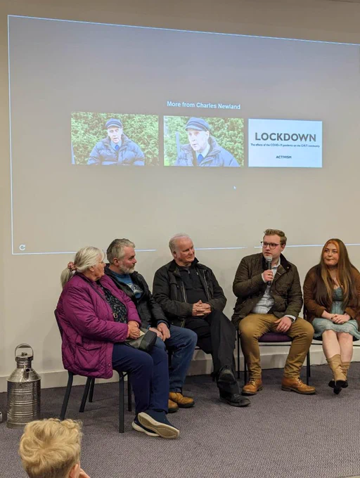 A panel of speakers sit in front of a screen and have a discussion.