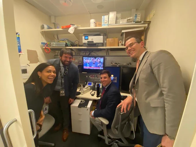 Bloomberg reporters smiling in a very small booth.