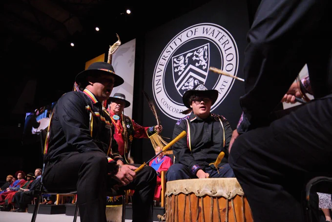 Indigenous drummers performing at convocation with Myeengun Henry holding the Eagle Staff in the background