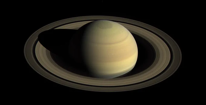 Saturn and its rings, seen against the darkness of space, from high above the ring plane, illuminated from the side by the Sun. The planet's north pole is fully in sunlight.