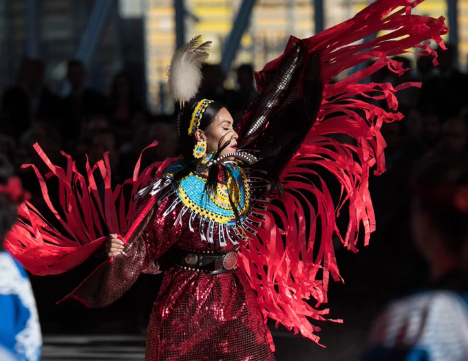 An Indigenous dancer in red regalia performing at Rogers Place