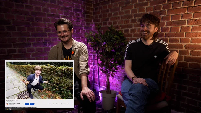 Luke and Tom B laughing looking at a clip of Tom with a wig crouched by a grate and some hedges. The clip is showing on the bottom left of the screen.