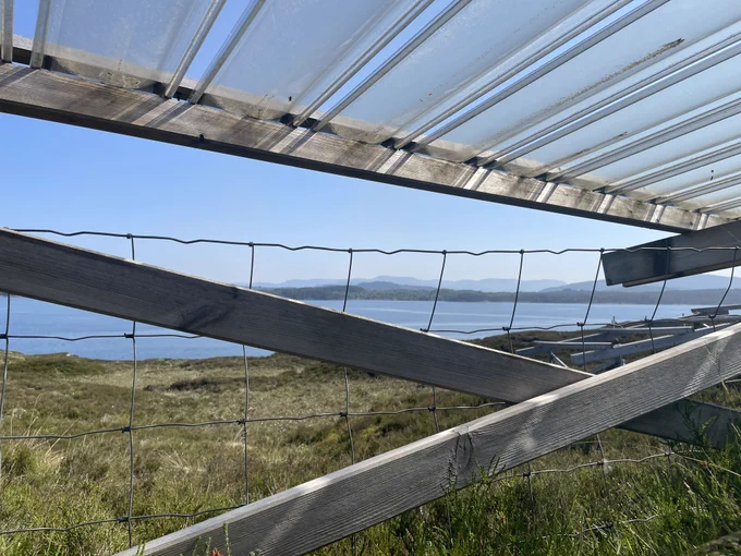View from underneath a rainout shelter that’s fenced in against sheep, toward the bay at a sunnier time.