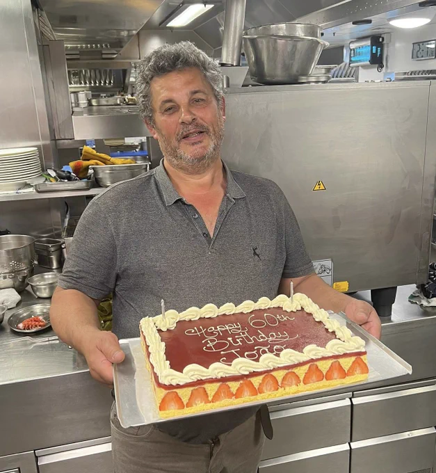 Joao from Madeira holding a massive strawberry birthday cake in the kitchen of Le Gavroche
