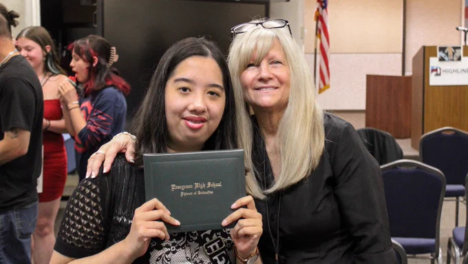 Student holding diploma with adult
