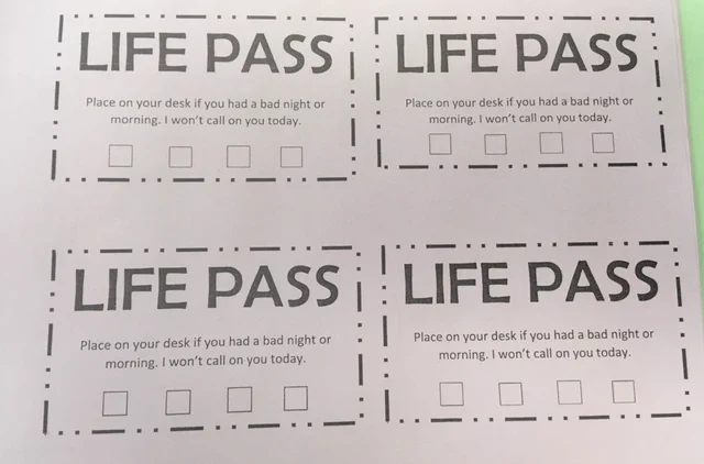 Photo of a printout titled "Life Pass: Place on your desk if you had a bad night or morning. I won't call on you today." There are four open boxes underneath.