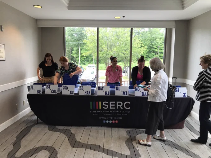 Registration table with black tablecloth with SERC logo, manned by four SERC staff members.