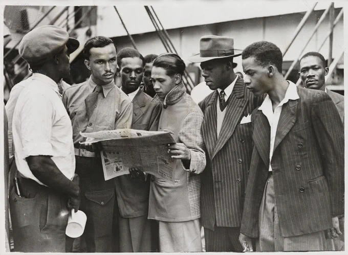 An image of a group of people waiting to disembark from the 'Empire Windrush', 21 June 1948. There are seven smartly dressed men gathered together to look at a newspaper.

Image Credit:
Science and Society Museum/ Universal Images Group
Rights Managed / For Education Use Only
