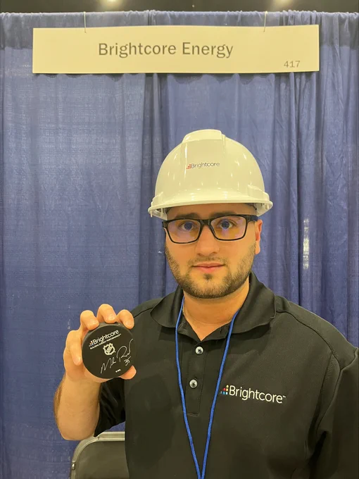 Brightcore’s Tyler Levy shows off a hockey puck signed by Brightcore Energy President Mike Richter.