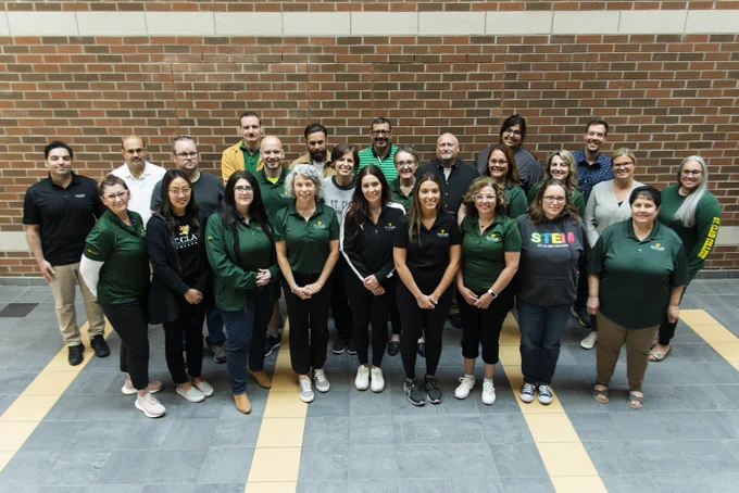 A group of St. Clair College faculty members wearing St. Clair swag in a group photo taken at Fanshawe College. 