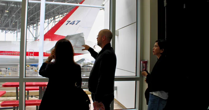 Photo of 2 people looking out window at airplane.