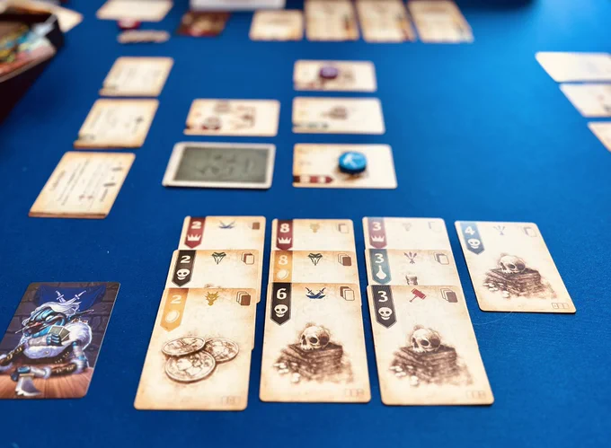 Cards in four suits are laid out in columns of three cards (with a single, 10th card in the rightmost column). The leftmost column are all 2s, the middle is 8,8,6, and the third is all 3s. The topmost row are all red suit. Above the tableau are a blurred out view of three central cards with tokens placed on two of them