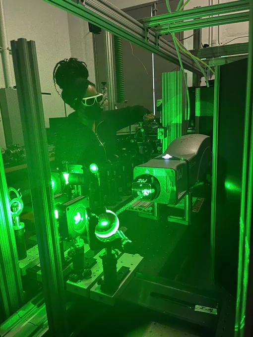 Woman working on optical equipment with green laser shining through