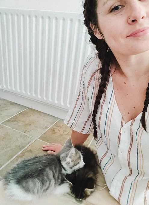 photo of turtletickles sitting on the floor with 2 small kittens on her lap