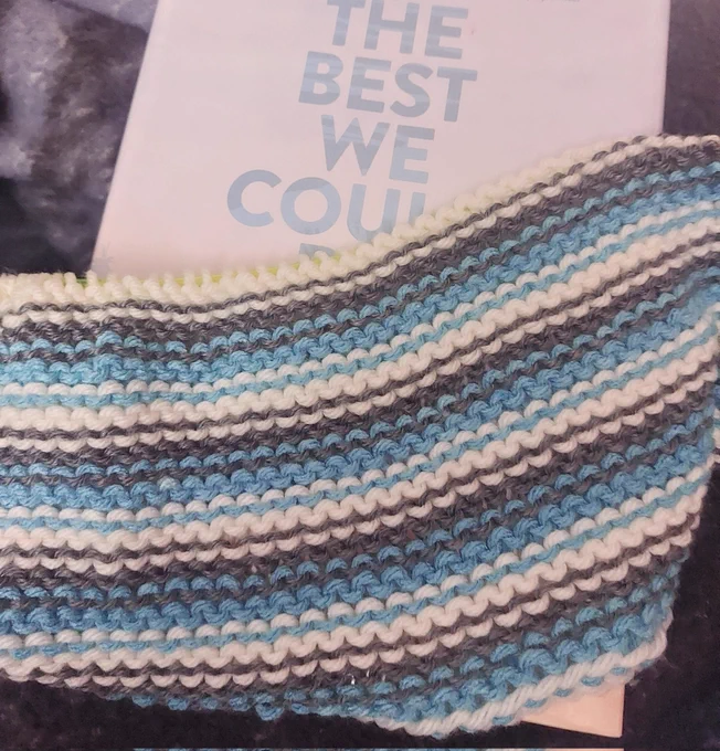 Grey, white, and teal striped fabric over a book with pale background and teal block letters