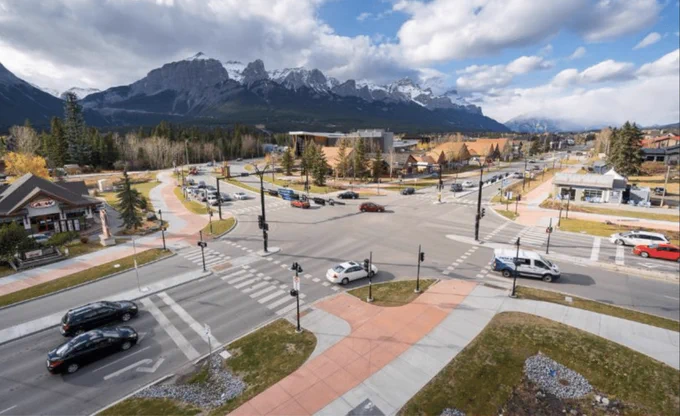 An aerial view of a protected intersection in suburban Canmore, Canada includes red-tinted separated cycle tracks.