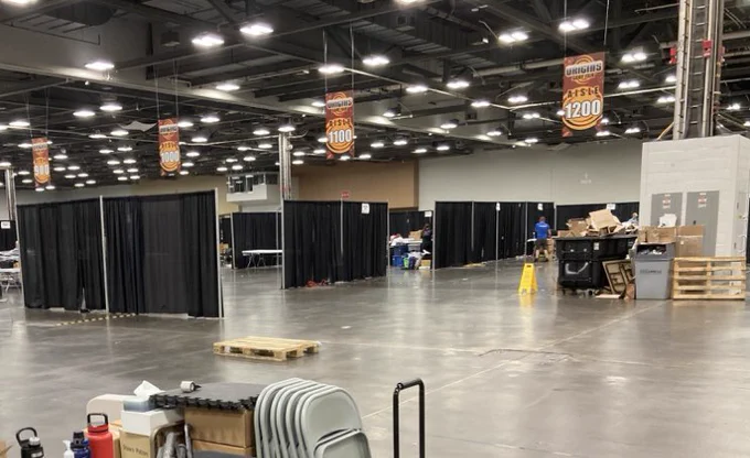 Shot of a mostly empty exhibit hall floor, some drapes and random chairs spread around