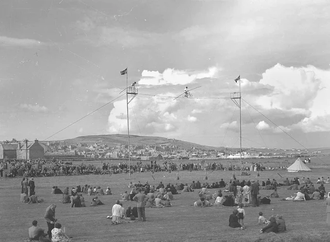 A black and white photograph of a high wire act at Stromness Shopping Week in 1953