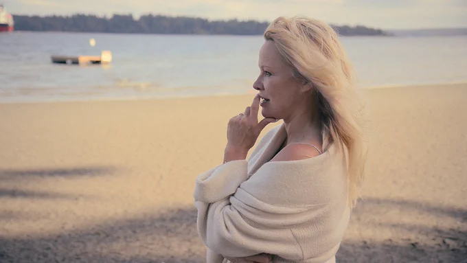 '90's superstar Pamela Anderson of "Bay Watch" fame stands in profile on the beach looking contemplative in a contemporary photo