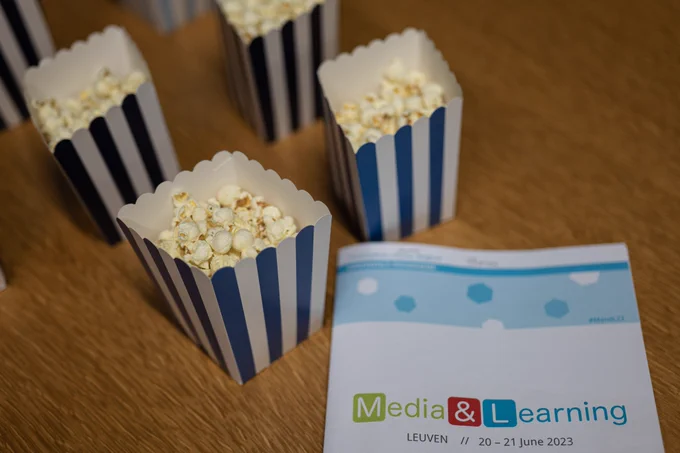 Photograph of pop corn boxed and 1 Media & Learning 2023 Conference Programme. 