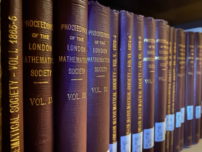 Photo of volumes of Proceedings of the London Mathematical Society on a shelf in the History of Science Collections at OU Libraries (maroon spines with gold lettering for title and volume; begins with vol. 1 1865-6).