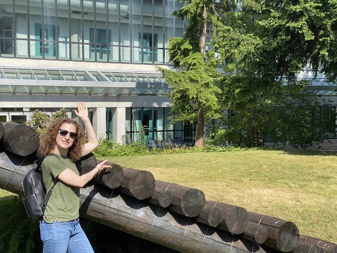 Sierra standing by a sculpture in front of the Chemistry building, presenting the building like Vanna White