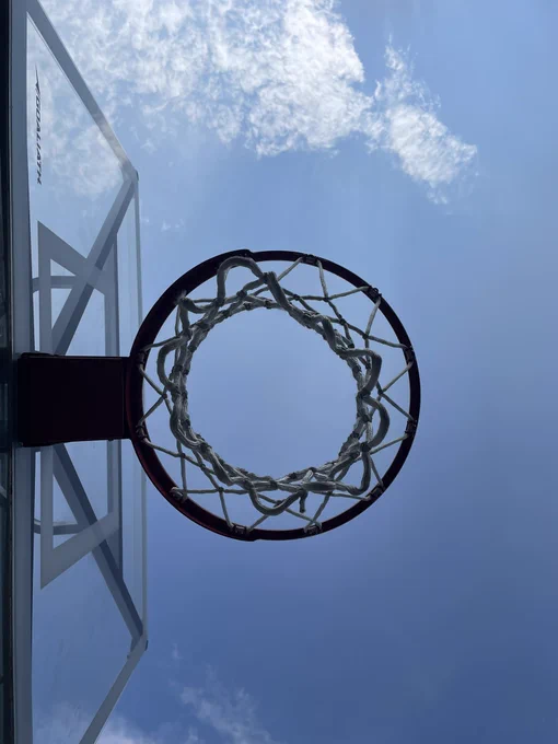 Looking up through a basketball hoop at a blue sky.