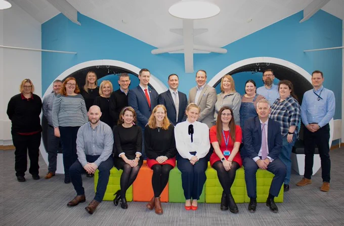 Meeting of counter-infringement colleagues at the IPO sat on a lime green sofa and stood in front of a blue wall, welcoming colleagues from the Police Intellectual Property Crime Unit and Border Force.