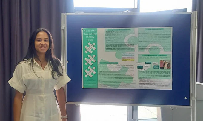 Jade standing next to her poster at the graduation conference