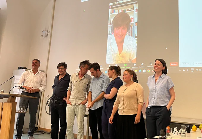 Die Teilnehmer:innen des Humanities Slam stehen nebeneinander und lachen in die Kamera. 
