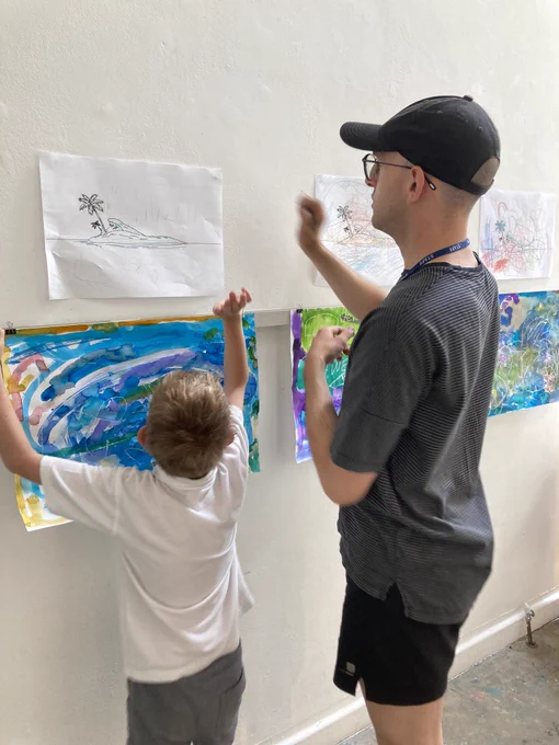 A pupil and the gallery curator hanging finished artwork on the wall.