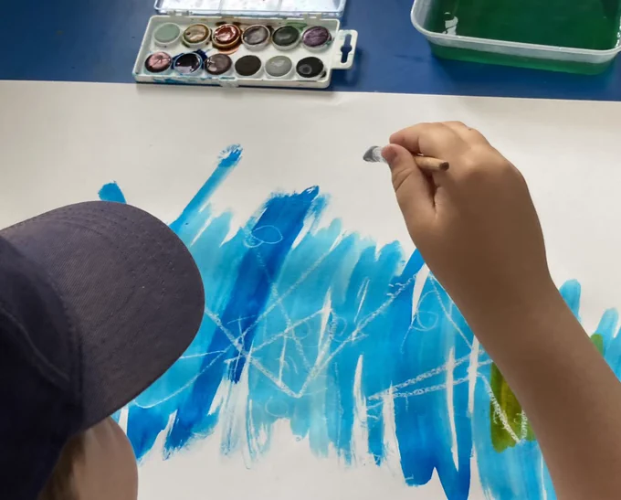 A pupil exploring the wax crayon and watercolour art-making technique.