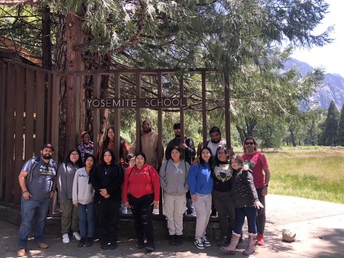 image of Allensworth middle and high school students and group leaders standing at the Yosemite School sign in Yosemite Valley, Yosemite National Park