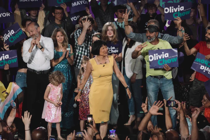 Olivia standing on stage with supporters behind her.