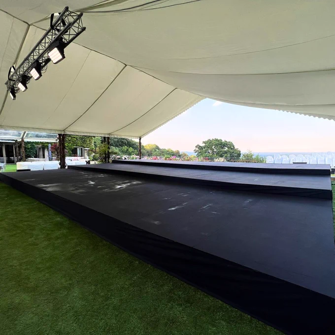 a 3 tiered stage covered with a roof and a countryside view in the background