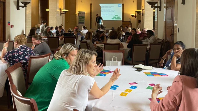 Delegates in discussion round a table in a Learning From afternoon event
