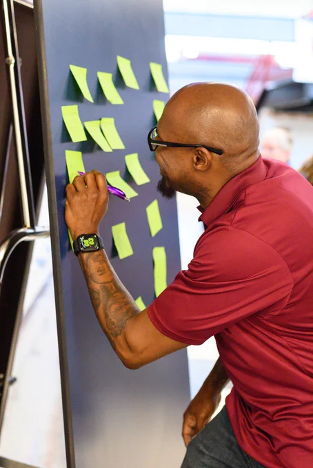 man writing on posted notes on the wall