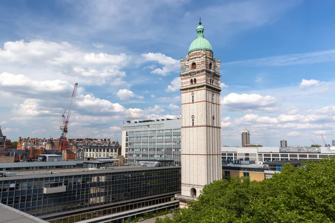 Imperial's Queen's Tower with a blue sky behind it and surrounded by campus buildings