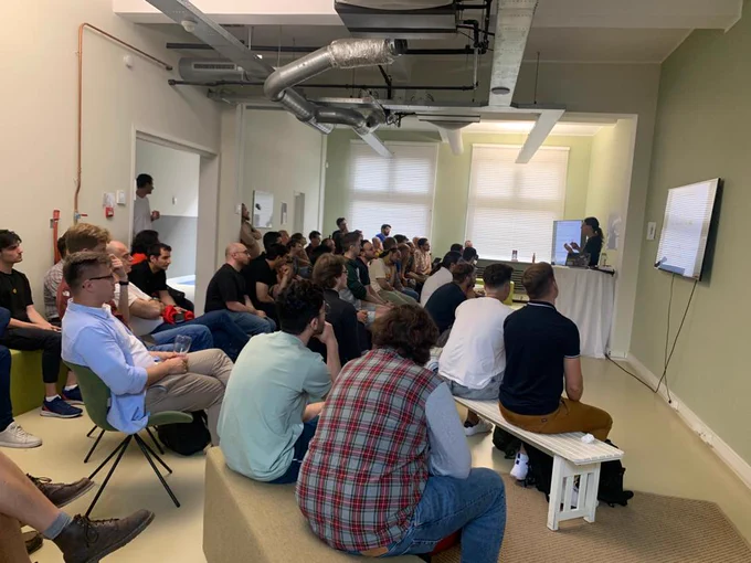 Picture taken from the back of a full room of people listening to a speaker