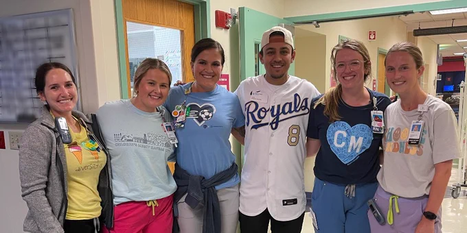 Nicky is standing with a group of nurses and they are all smiling.